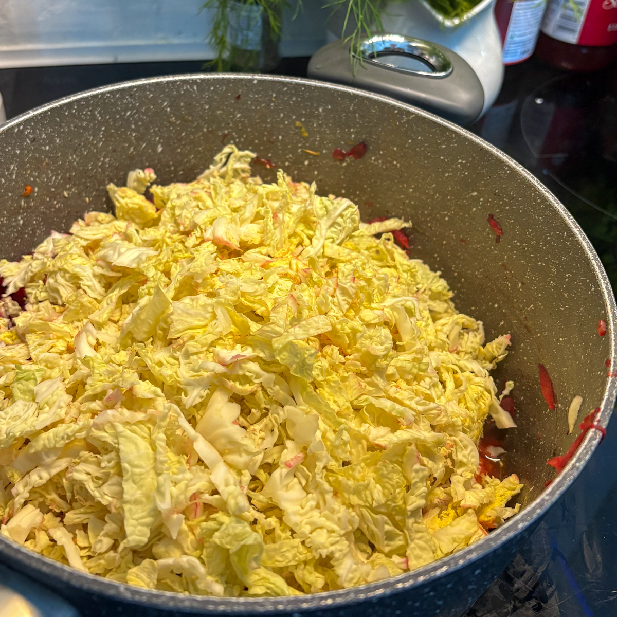 Thinly sliced white cabbage added to the pot during the cooking process of a homemade Chicken Borscht.