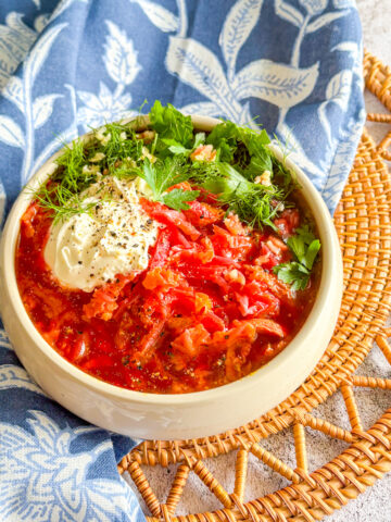 A steaming bowl of hearty Chicken Borscht topped with a generous dollop of sour cream and fresh dill.