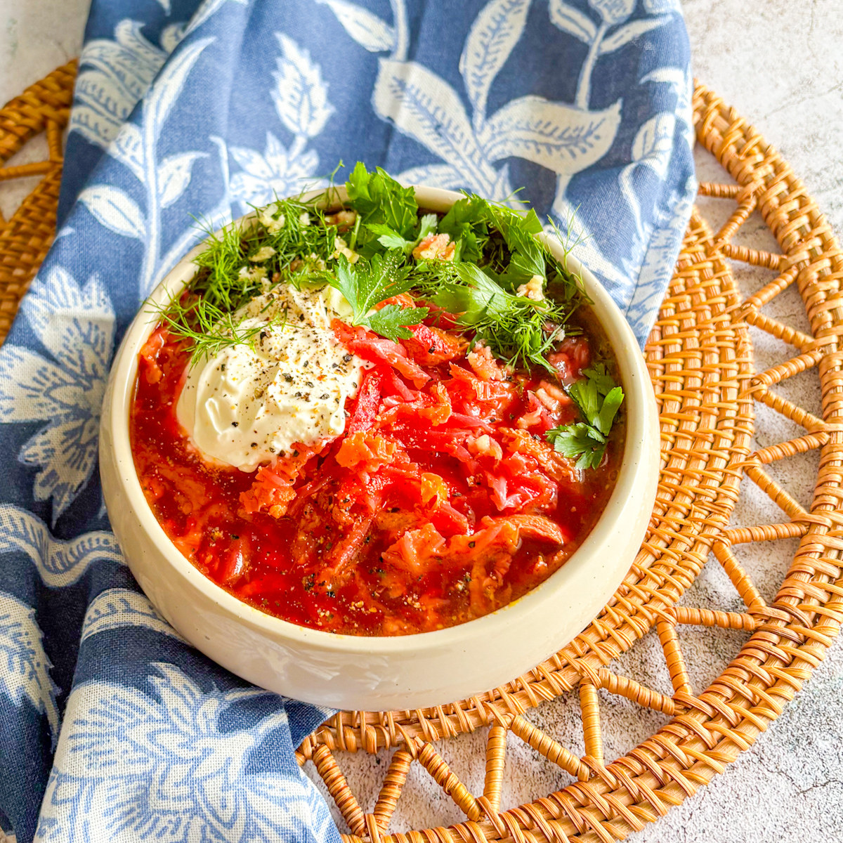 A steaming bowl of hearty Chicken Borscht topped with a generous dollop of sour cream and fresh dill.