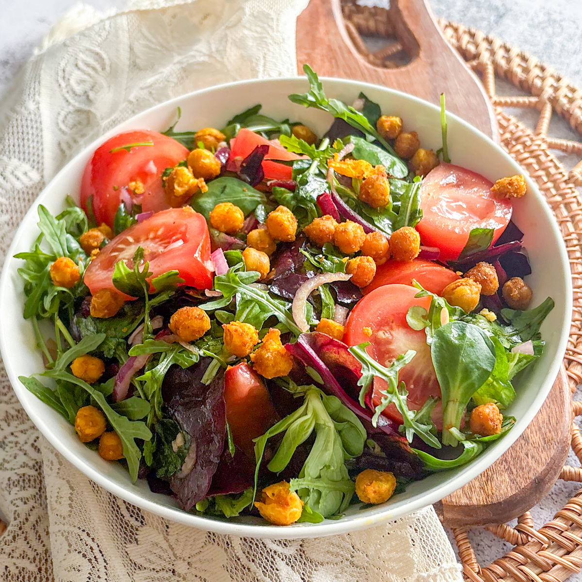 Easy tomato and chickpea salad recipe served in a white ceramic bowl on a wooden serving board.