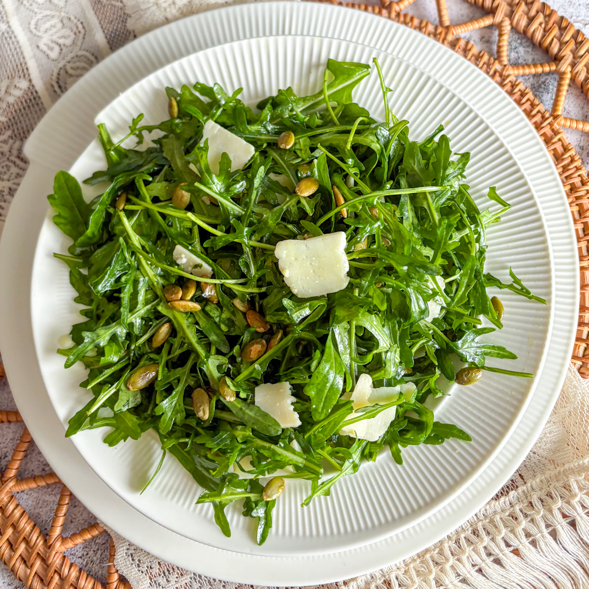 A light and crisp easy rocket salad showing vibrant green leaves, pumpkin seeds, and cheese shavings.