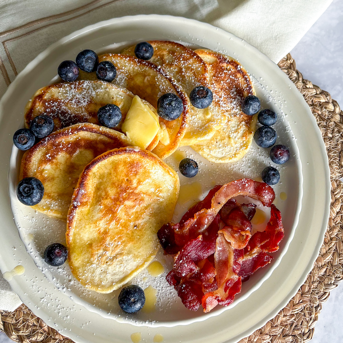 An angled shot focusing on the light and airy texture of thick buttermilk pancakes with blueberries and melting butter.