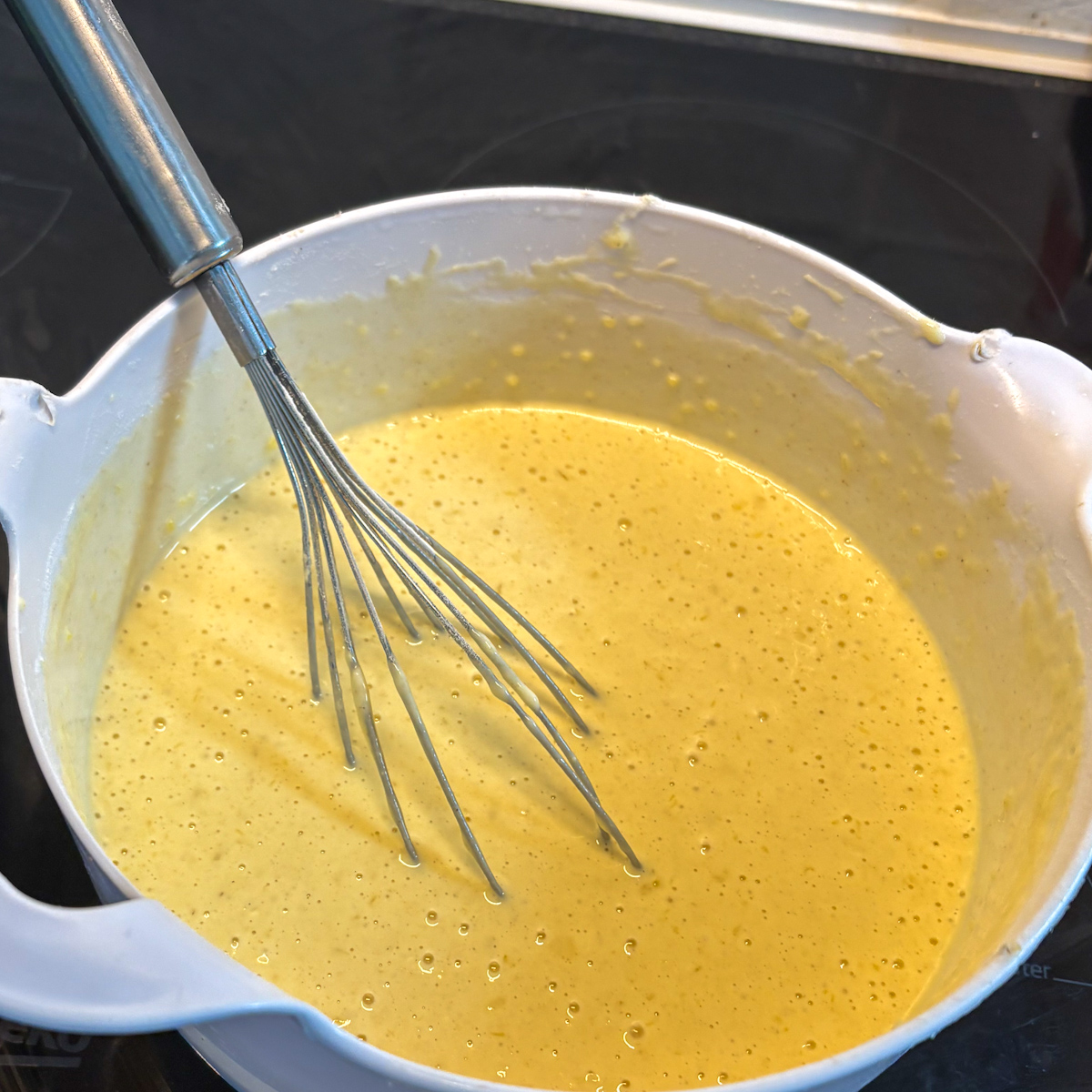 A large bowl holding the smooth, silky batter resting with visible air bubbles for fluffy buttermilk pancakes.