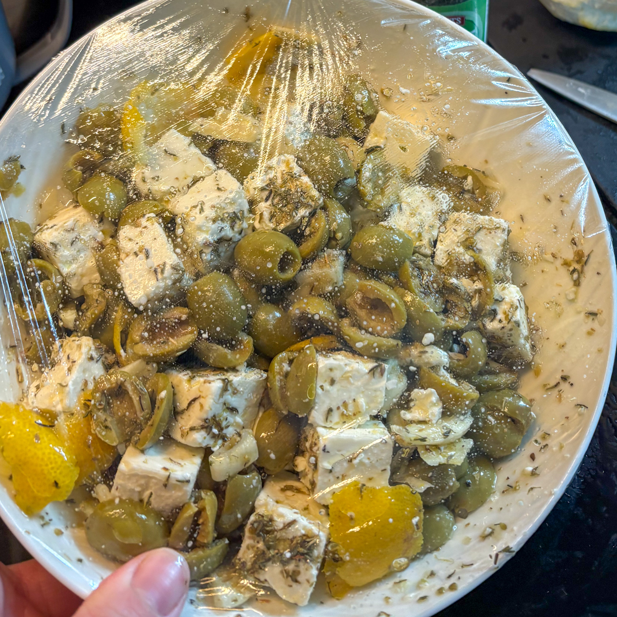 Marinated feta and olives covered with cling film for overnight marinating