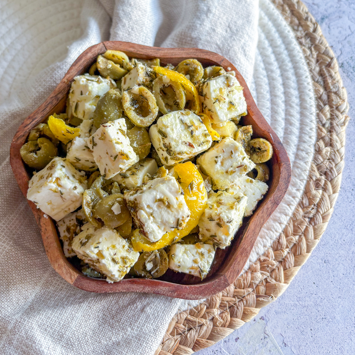 Overhead view of marinated feta appetiser with olives and lemon zest