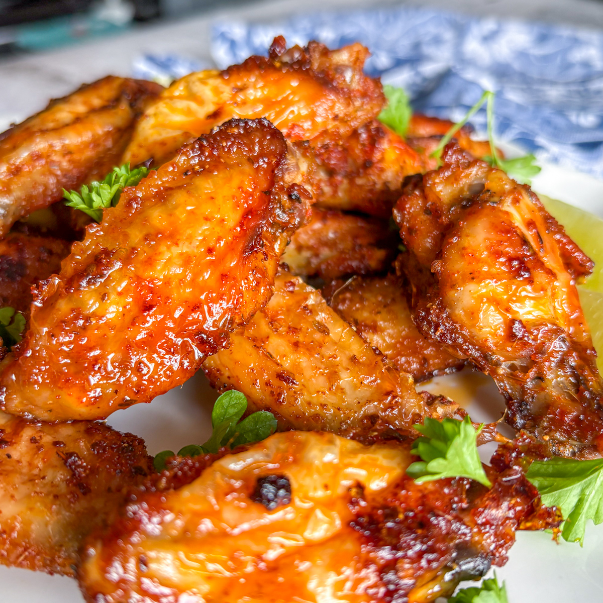 Close-up of crispy pantry staples chicken wings with parsley and lime on a plate.
