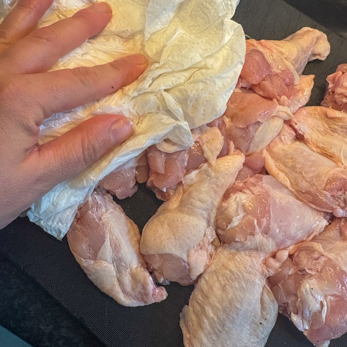 Patting chicken wings dry with kitchen paper before making pantry staples chicken wings.