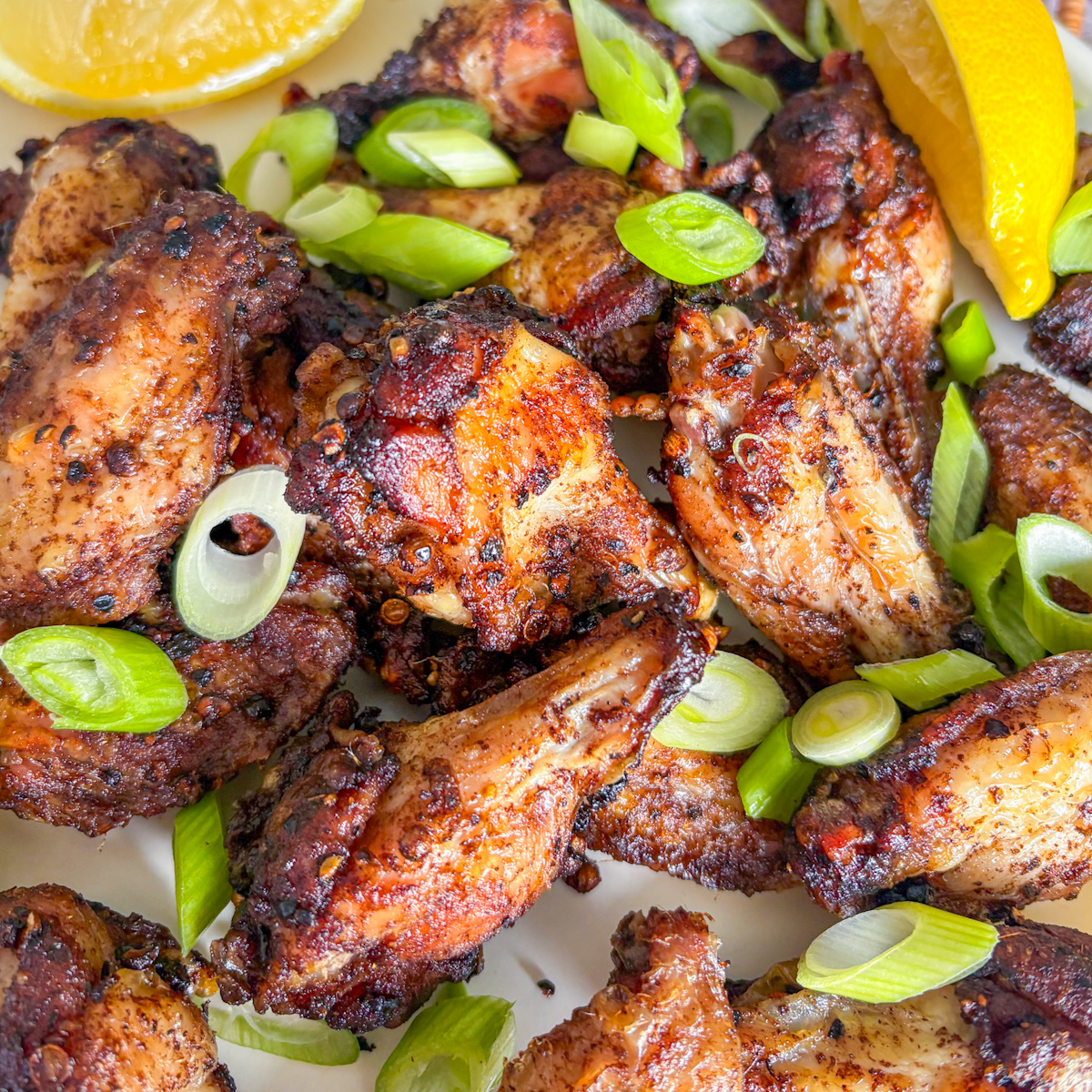 Close-up of Crispy Peppercorn Coriander Chicken Wings with golden skin and sliced spring onions on top.