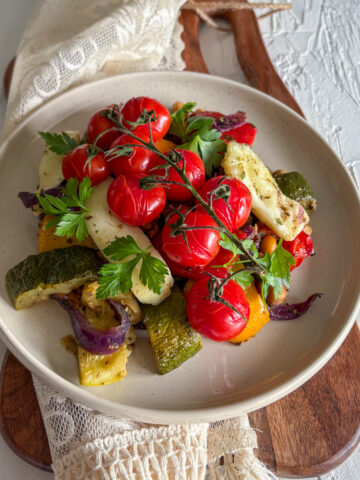 A healthy vegetarian dinner of roasted vegetables and halloumi, beautifully garnished with fresh parsley.