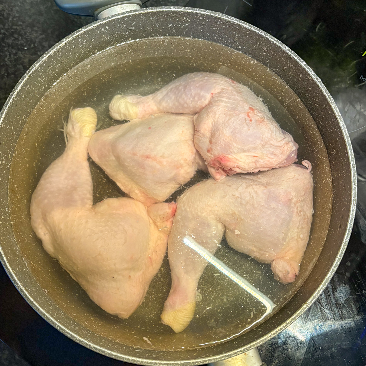 Raw chicken legs in pot of cold water ready for blanching for Russian chicken soup