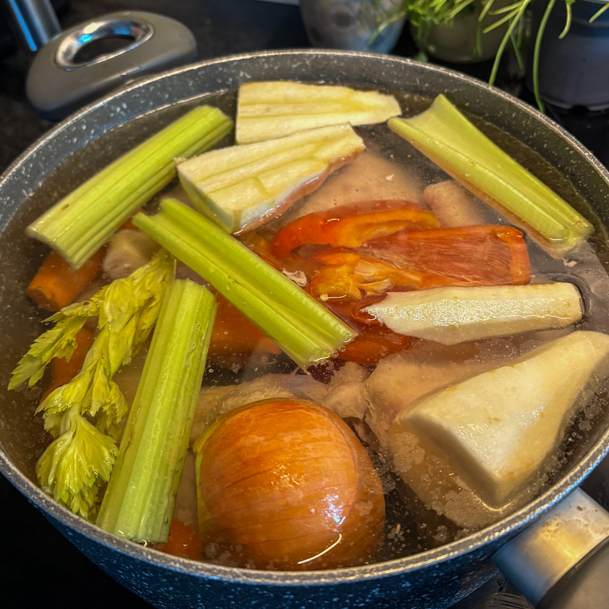 Fresh root vegetables added to chicken stock pot for Russian chicken soup