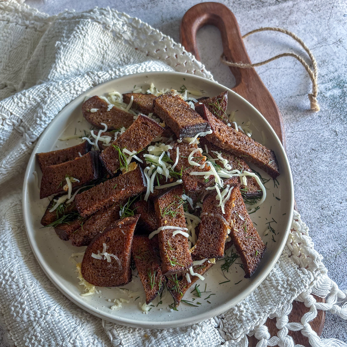A top-down view of a plate filled with crunchy Garlic grenki recipe strips with dill and mozzarella