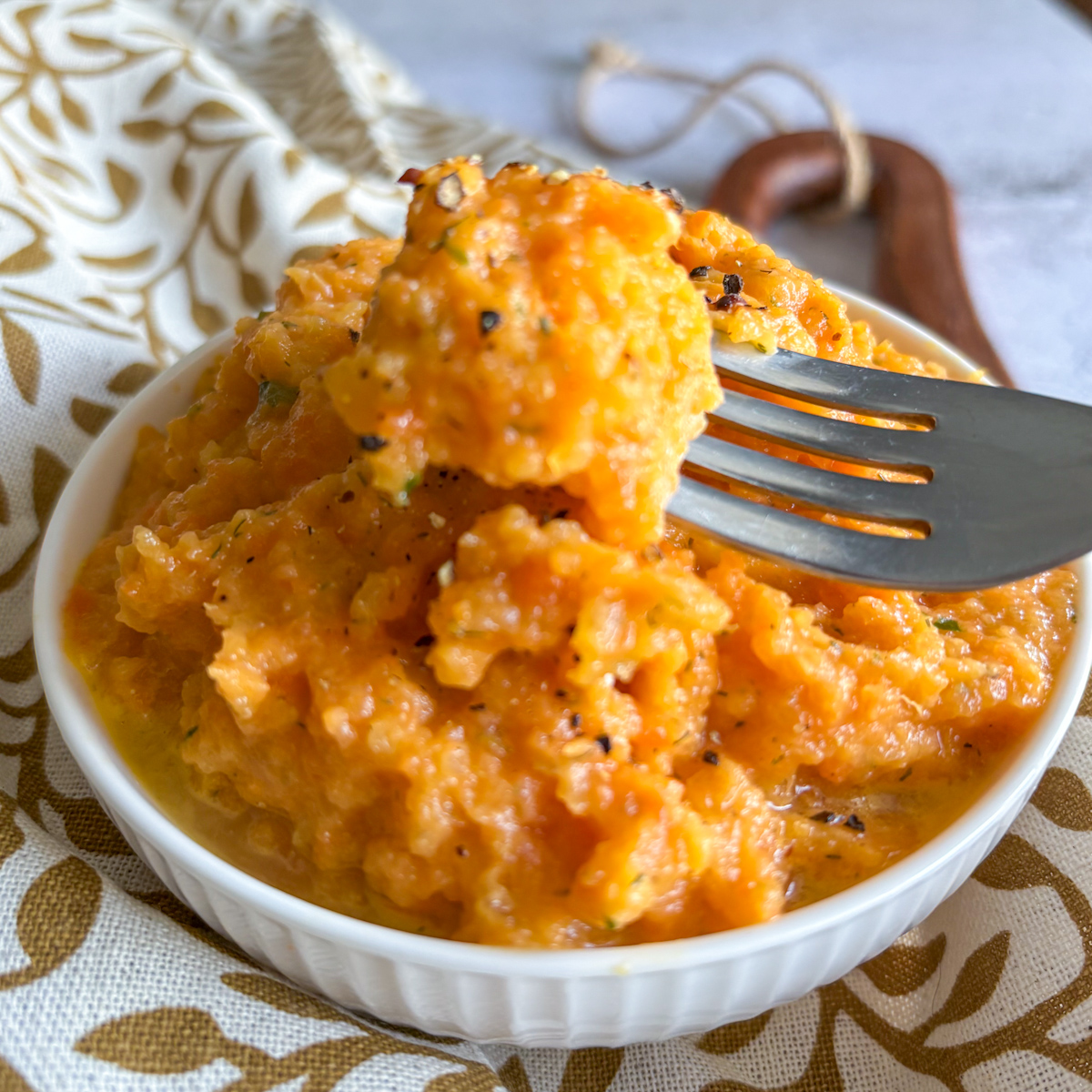 Rustic carrot and turnip mash with garlic butter topped with herbs and pepper