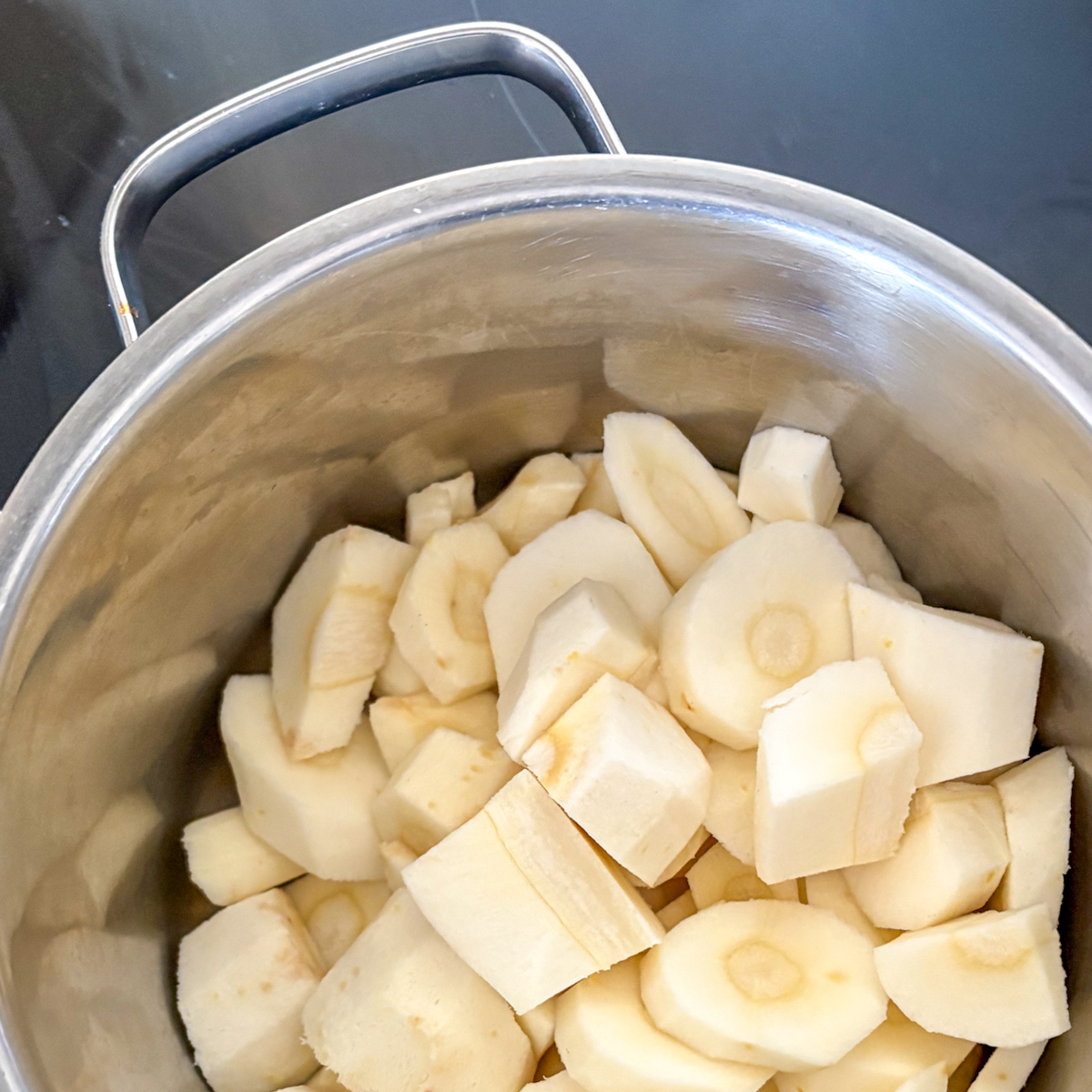  Peeled parsnips cut into rounds in large stainless pot, ready to boil for easy parsnip mash