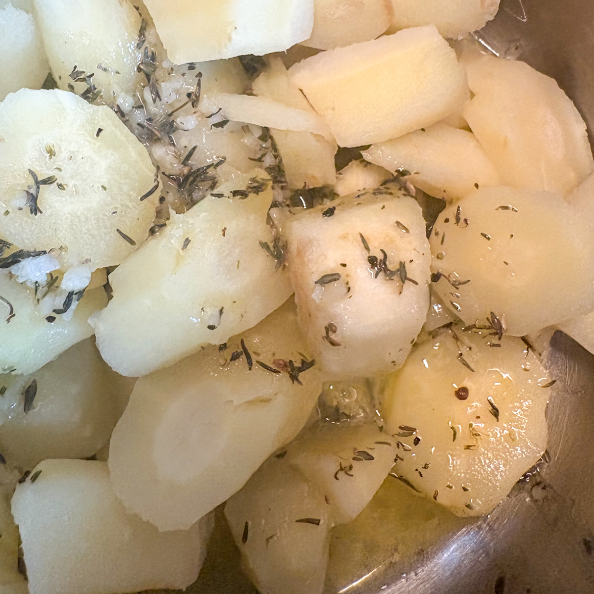 Boiled parsnip rounds with thyme and sea salt in pot, ready to mash for creamy parsnip mash