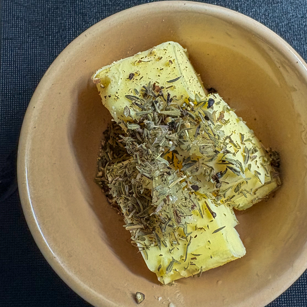 Unsalted butter with minced garlic and dried thyme in small bowl for buttery parsnip mash recipe