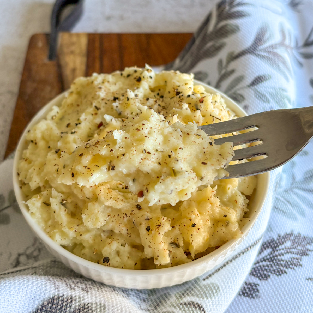 Smooth creamy parsnip mash topped with cracked pepper and dried thyme in a fluted white bowl