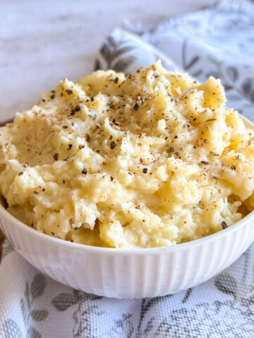 Best parsnip mash recipe with butter and garlic, plated in white ceramic bowl with herbs on top