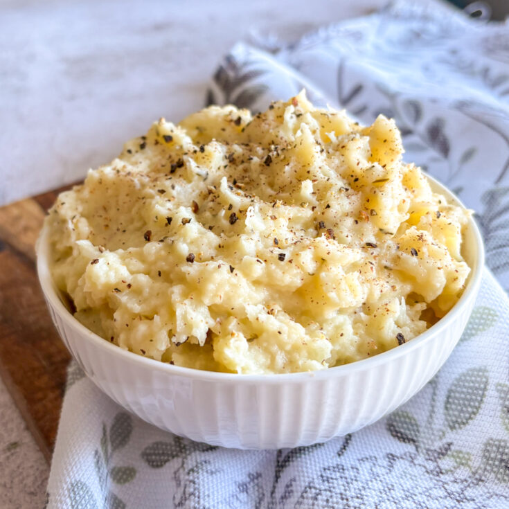 Best parsnip mash recipe with butter and garlic, plated in white ceramic bowl with herbs on top