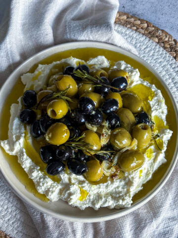 Mediterranean appetiser with warm marinated olives spooned over silky whipped feta