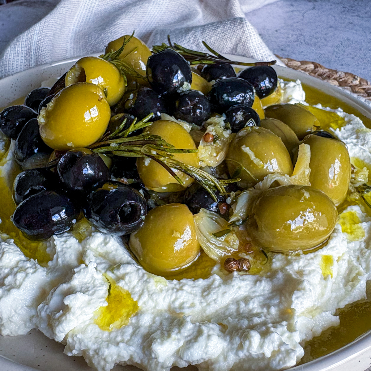 Close-up of marinated olives and whipped feta with rosemary, garlic and herb-infused oil