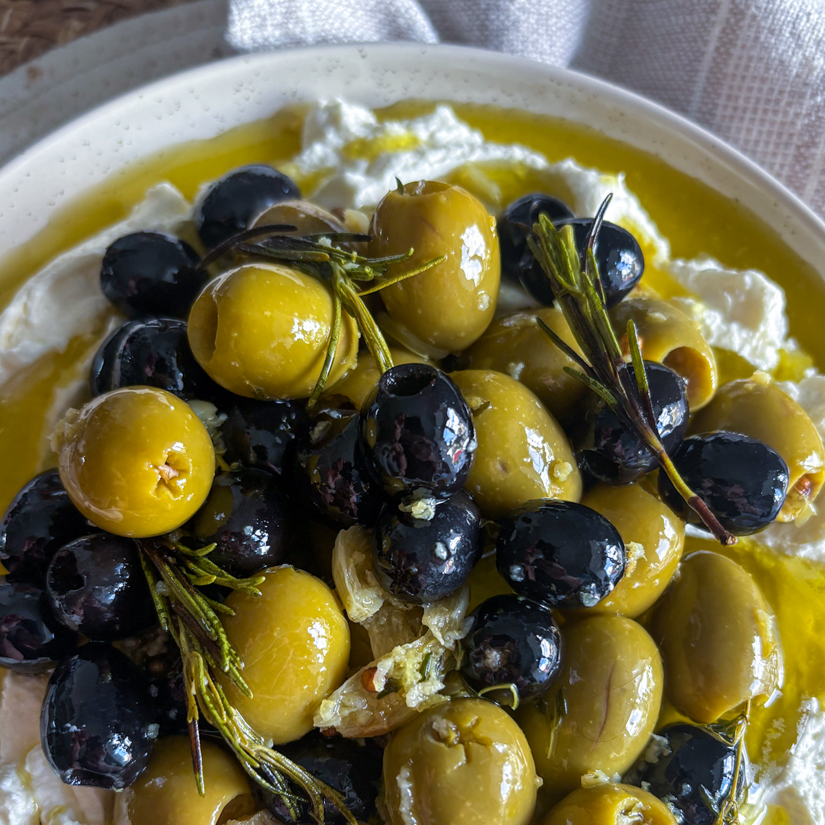 Whipped feta recipe topped with herby marinated olives and drizzled olive oil