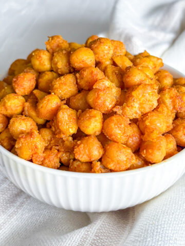 Eye-level view of a generous heap of crispy pan-fried chickpeas served in a white fluted bowl.