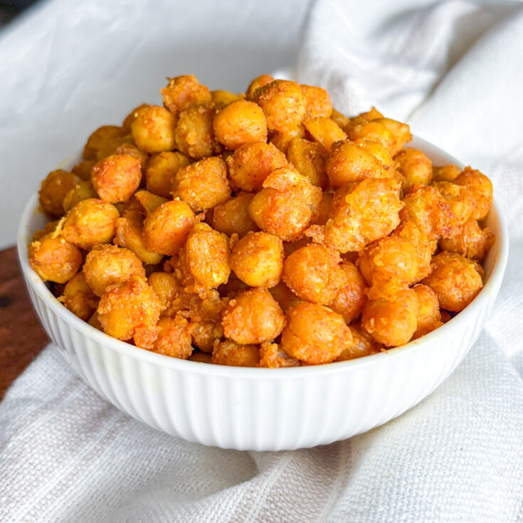 Eye-level view of a generous heap of crispy pan-fried chickpeas served in a white fluted bowl.
