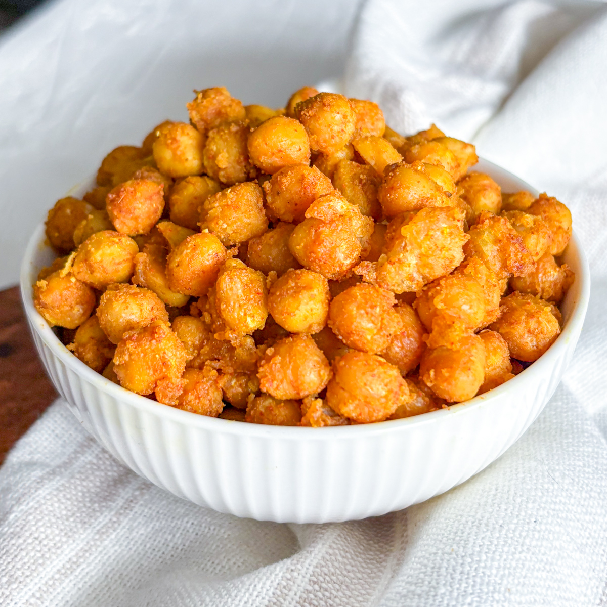 Eye-level view of a generous heap of crispy pan-fried chickpeas served in a white fluted bowl.