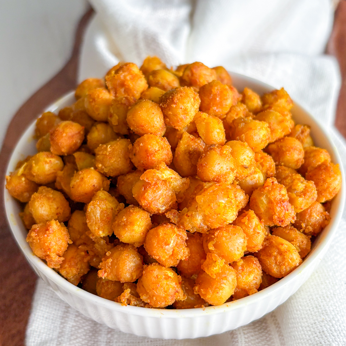 A white bowl filled to the brim with a healthy savoury vegan snack made from perfectly cooked pan-fried chickpeas.