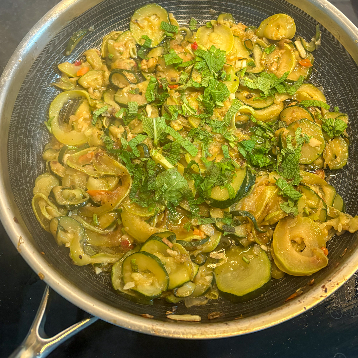 Slow-braised courgettes with mint and lemon finished in a stainless-steel frying pan
