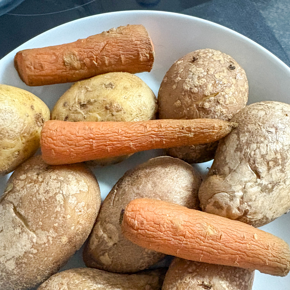 Boiled potatoes and carrots with skins on for vinaigrette salad recipe
