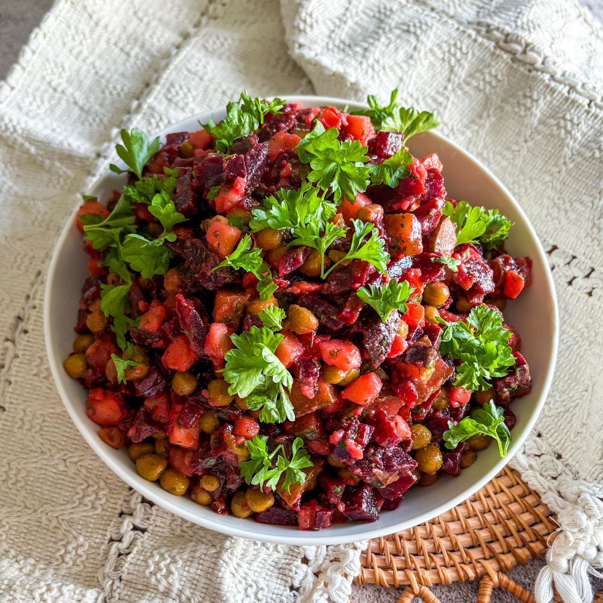 Russian vinaigrette recipe in a white bowl topped with fresh parsley
