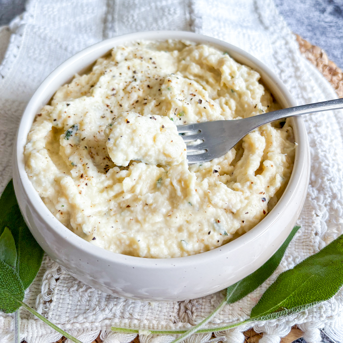 Fork lifting a bite of silky celeriac purée from a white bowl