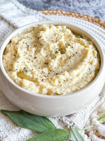 Creamy celeriac purée in a white bowl topped with black pepper