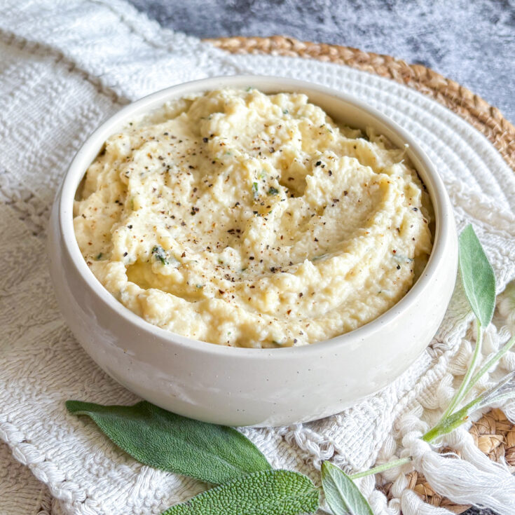 Creamy celeriac purée in a white bowl topped with black pepper