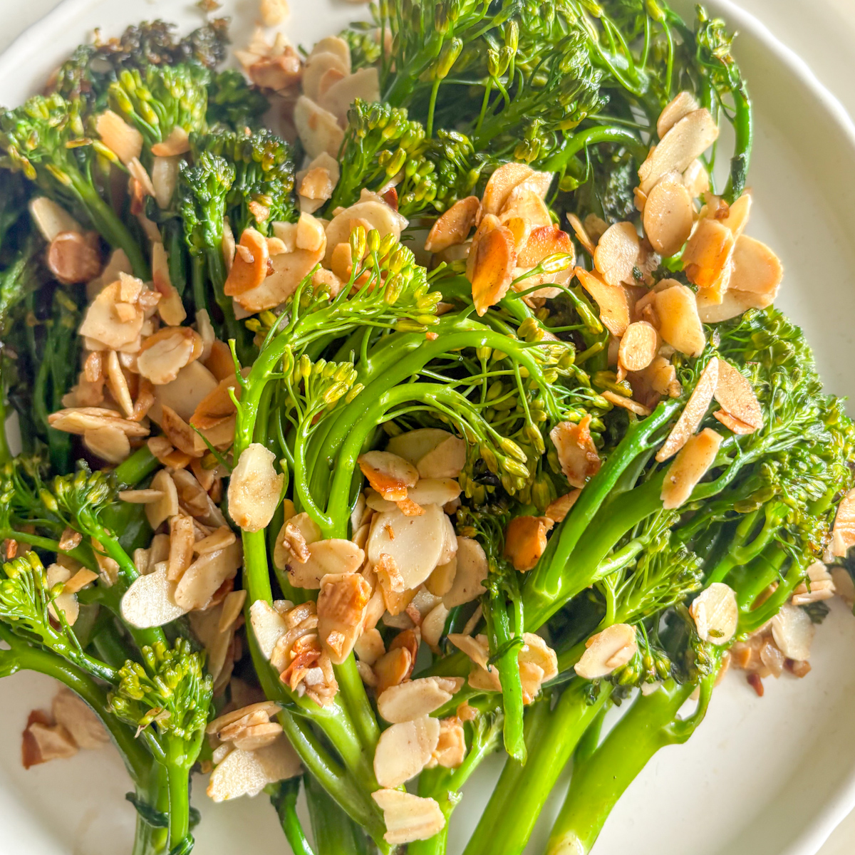 Close-up of charred broccolini stems coated in buttery toasted garlic almonds