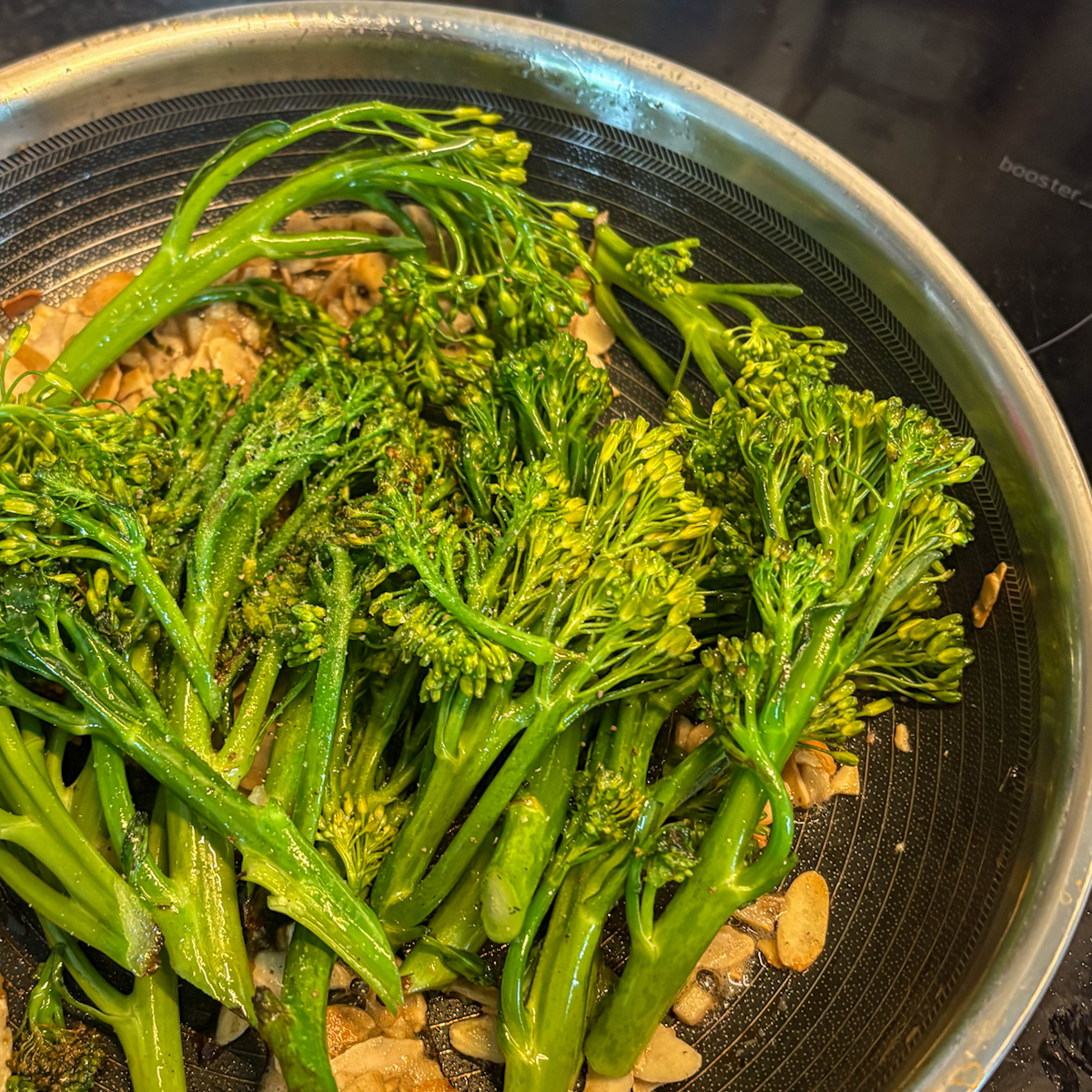 Charred broccolini tossed with toasted almonds and garlic butter in frying pan