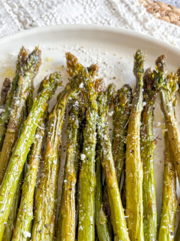 Roasted asparagus with parmesan and lemon zest on a white plate, easy 15-minute side dish.