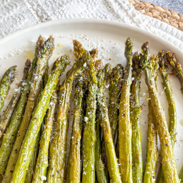 Roasted asparagus with parmesan and lemon zest on a white plate, easy 15-minute side dish.
