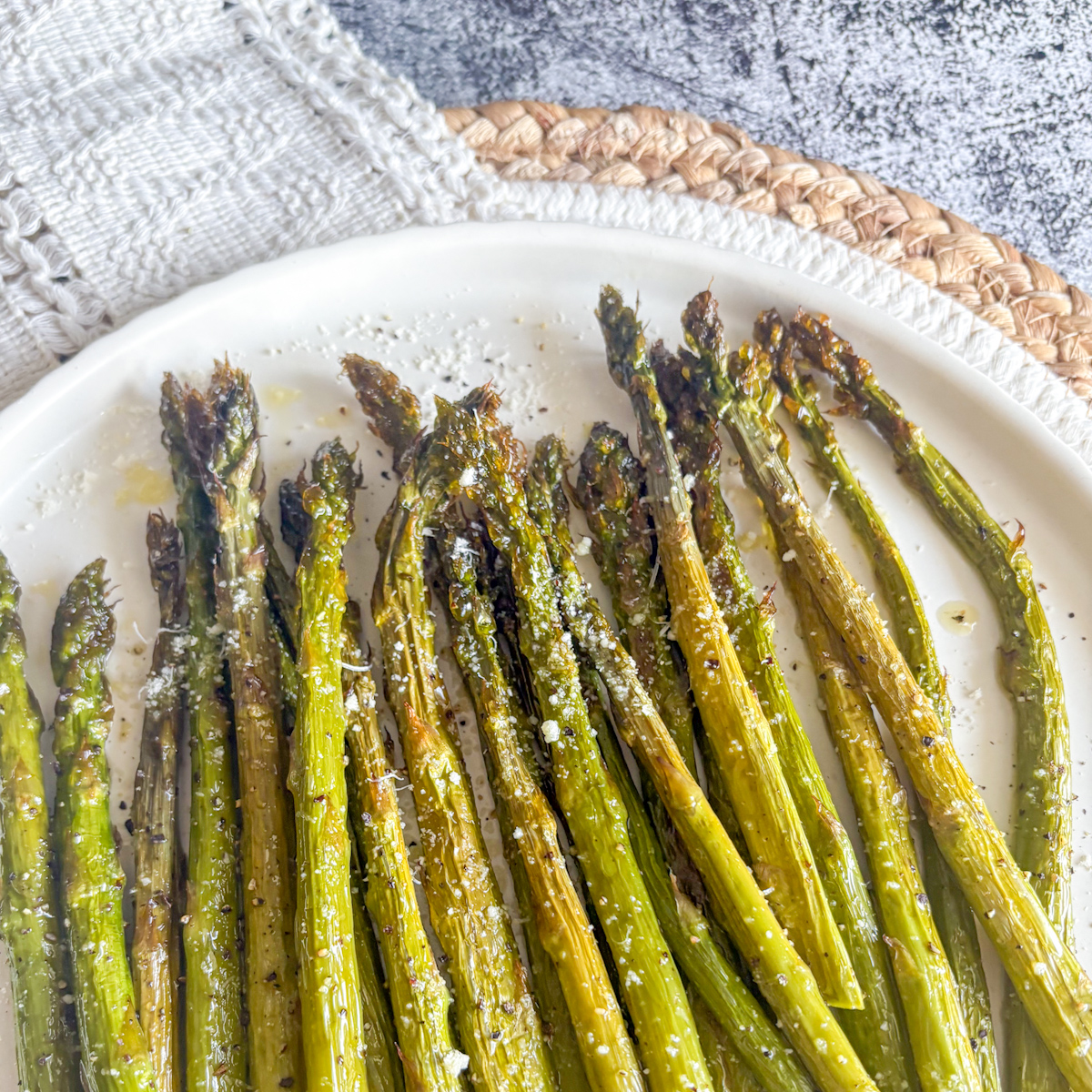 Crispy roasted asparagus with charred tips, parmesan and black pepper, served as a quick side dish.