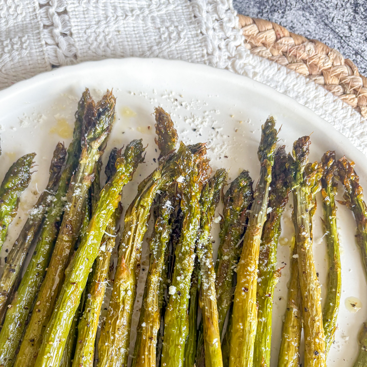 Roasted asparagus tips with golden brown charred edges and fine grated parmesan on a serving plate.