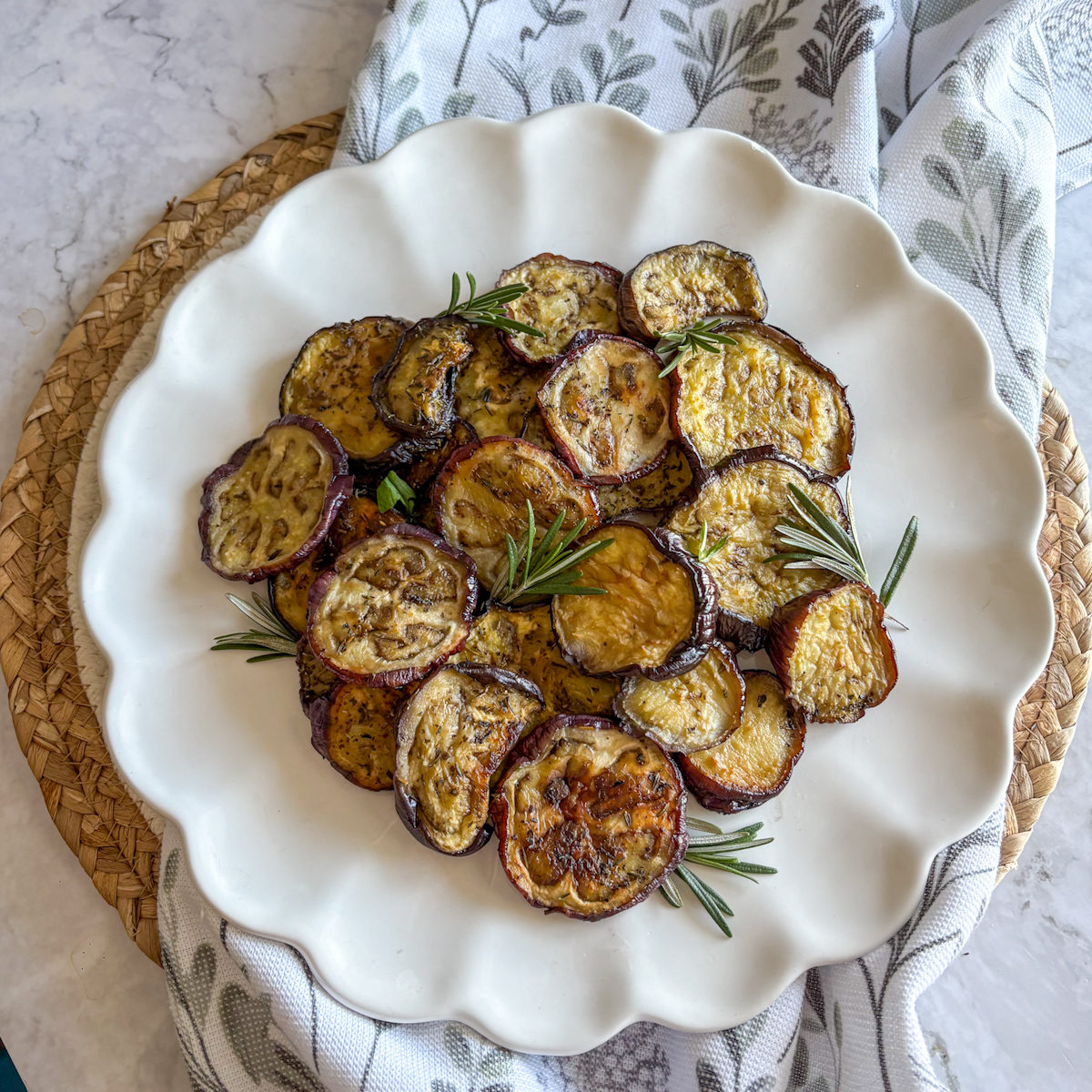 Roasted aubergine rounds with caramelised edges and fresh rosemary leaves