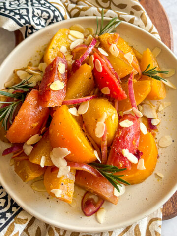 Braised beetroot wedges in skillet coated in glossy white wine vinegar glaze with red onion.