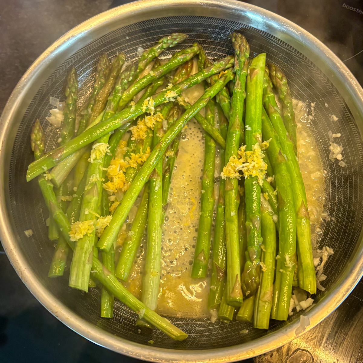 Pan-steamed asparagus in skillet topped with lemon zest mixture before serving.