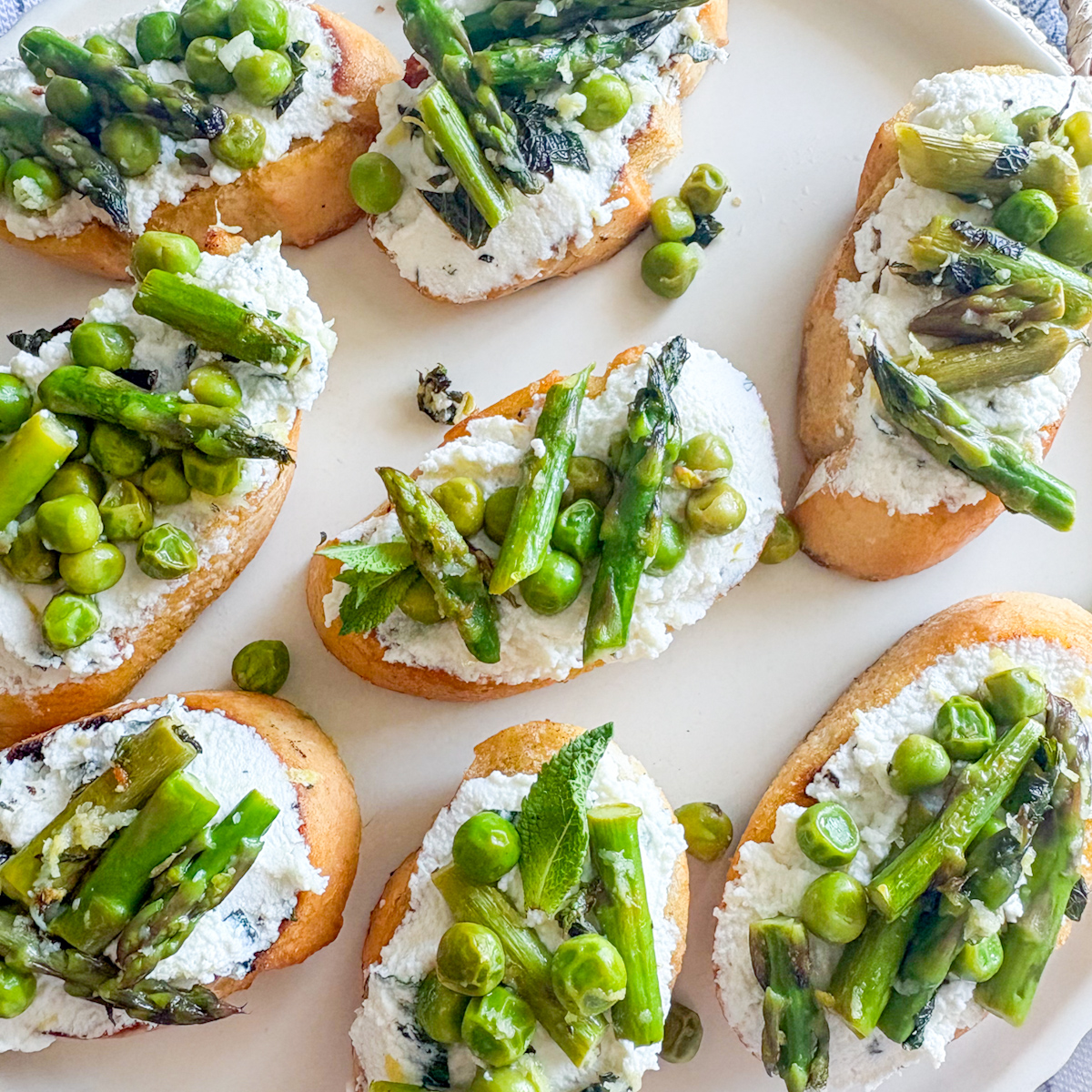 Close-up of pea and asparagus crostini with whipped ricotta, mint and asparagus tips