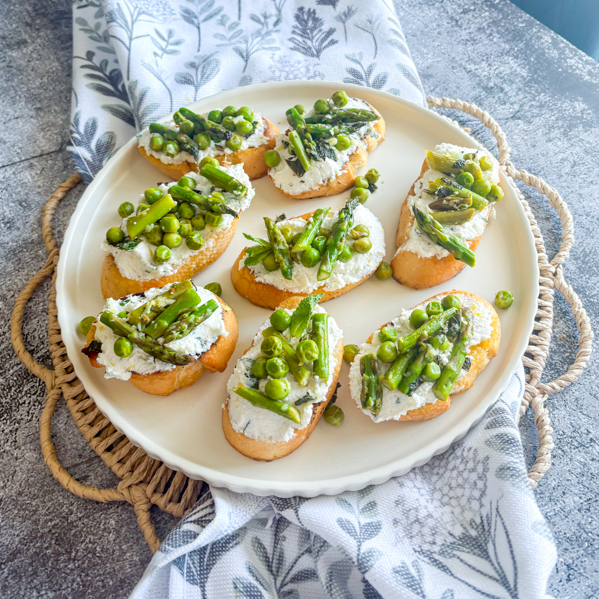 Overhead view of pea and asparagus crostini with whipped lemon ricotta, fresh mint and spring peas