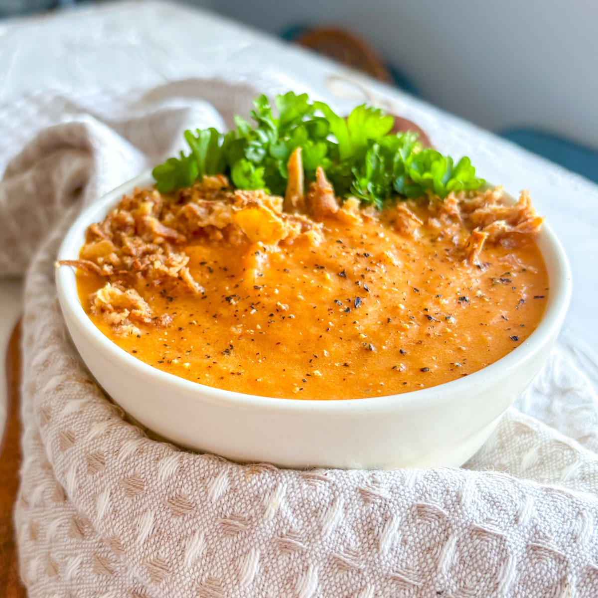 Creamy roasted carrot and ginger soup served simply with crispy onions and fresh parsley.