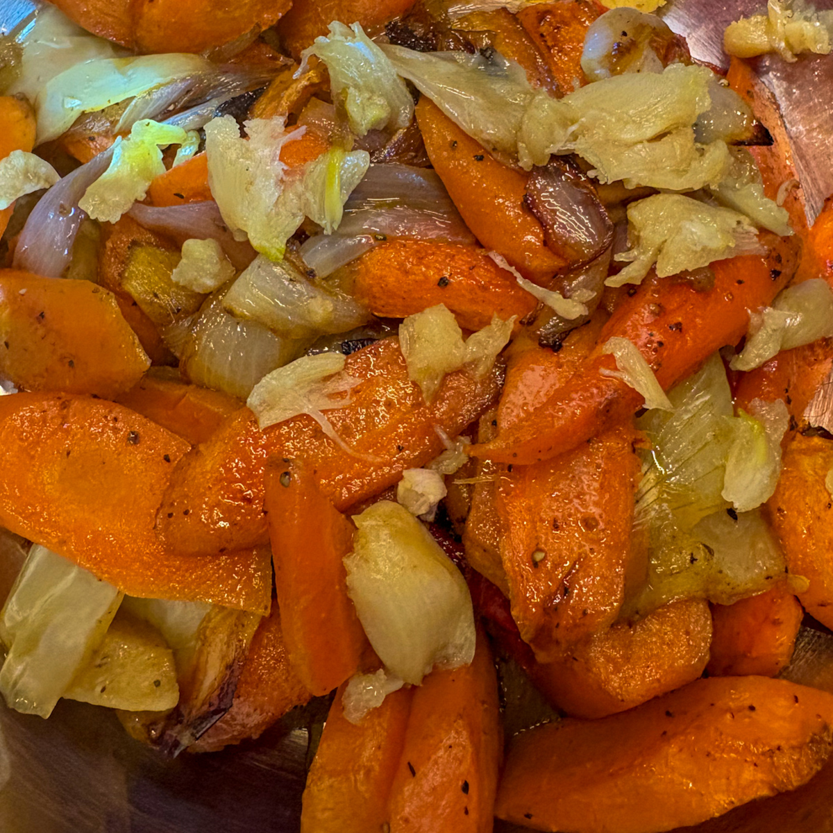  Roasted carrots, shallots, onion and garlic for roasted carrot and ginger soup recipe in a pot.