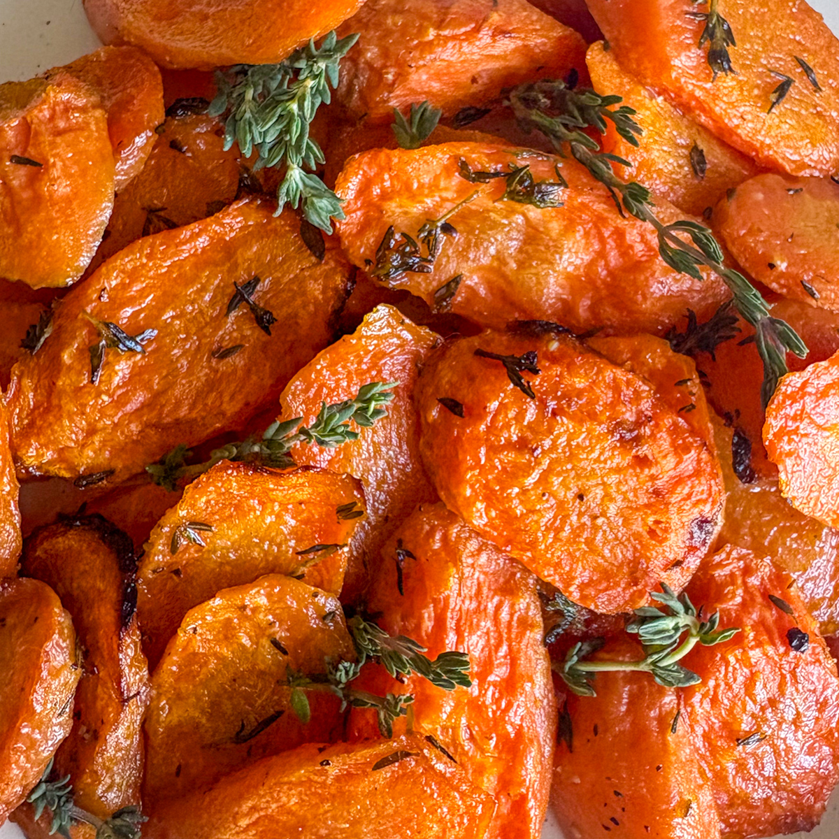 Close-up of roasted carrots with thyme showing brown crispy edges and fresh thyme leaves